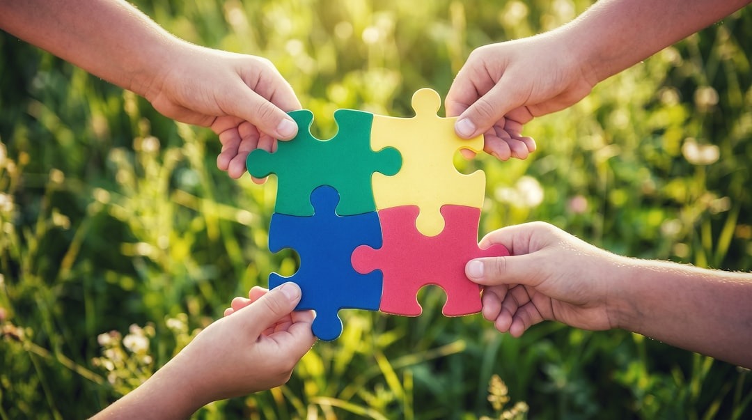 Four hands connecting puzzle pieces to form a square.