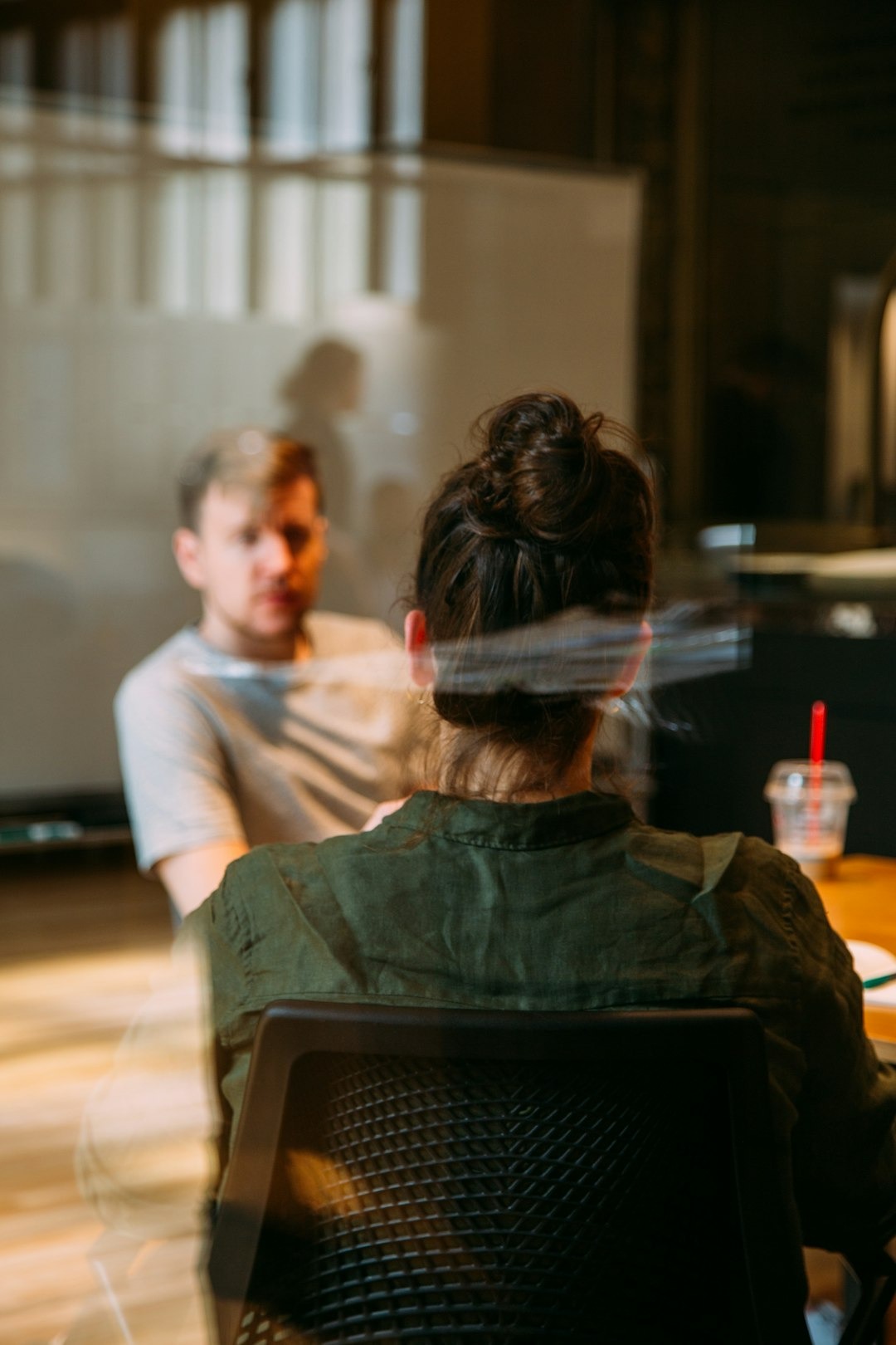Person in a bun sits in a chair during a meeting.